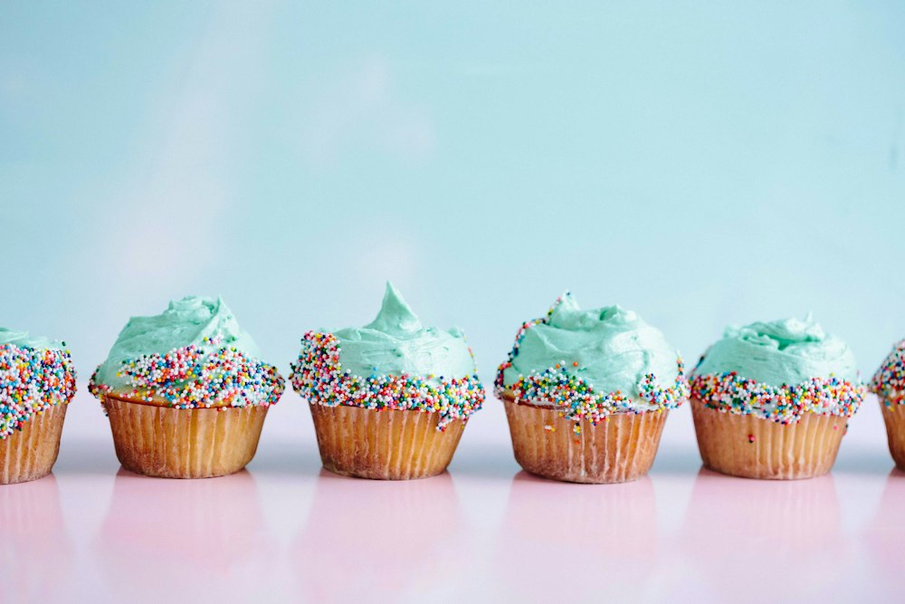 Cupcakes de cobertura azul e confeitos, em fundo pastel