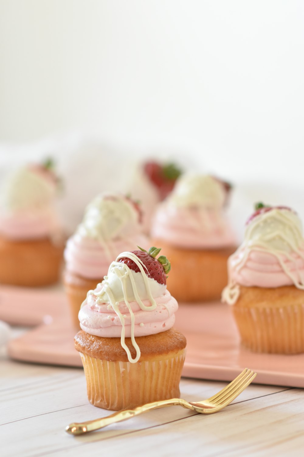Cupcakes artesanais com creme rosa e calda de chocolate branco
