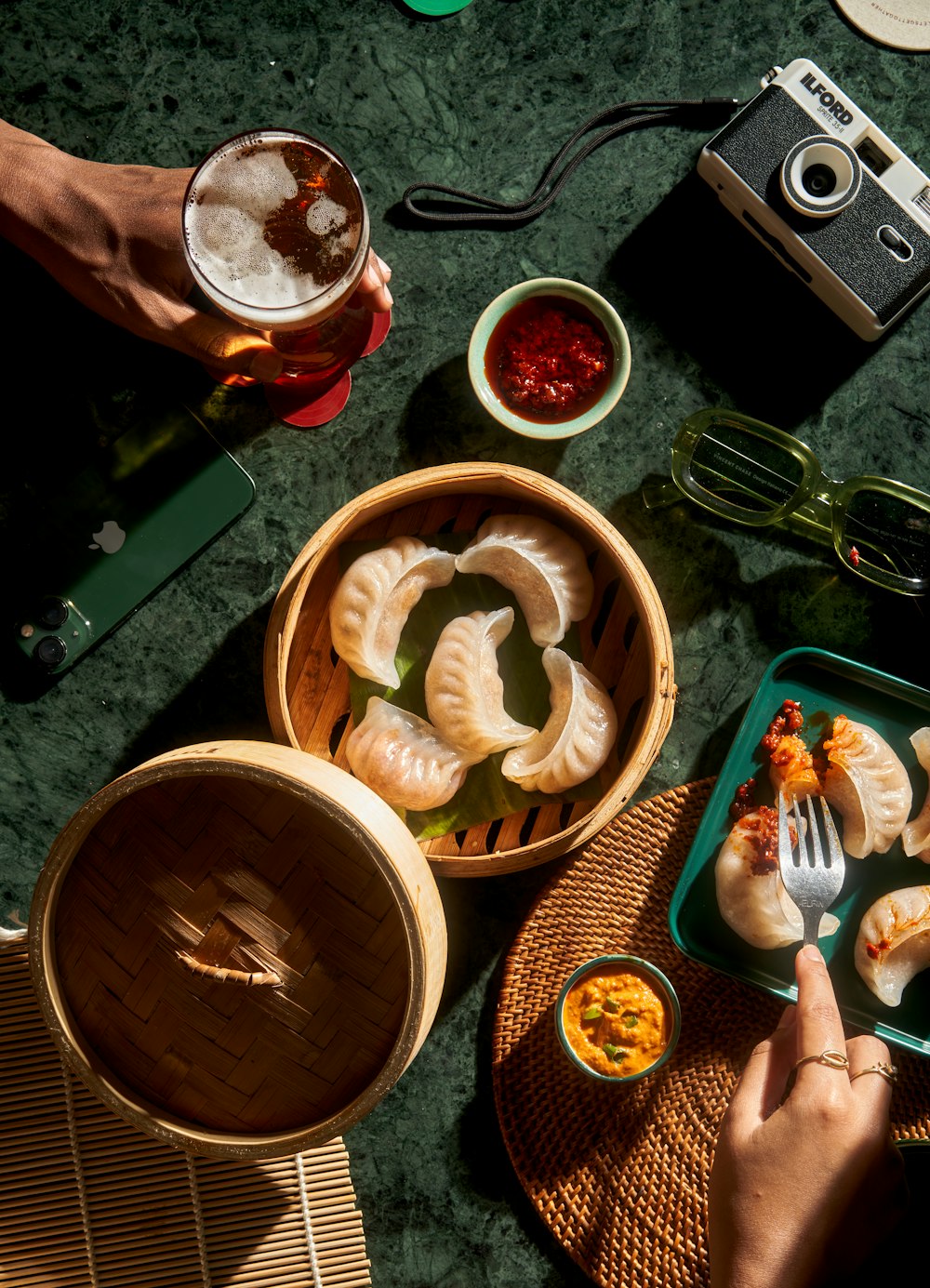 Dim sum e acompanhamentos sobre uma mesa verde escura