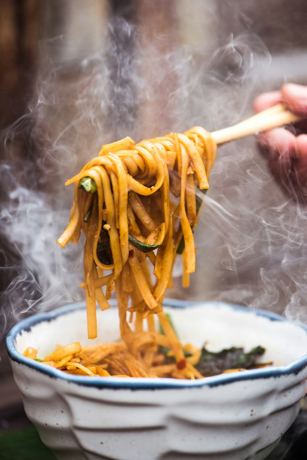 Fios de macarrão lo mein levantados por hashis