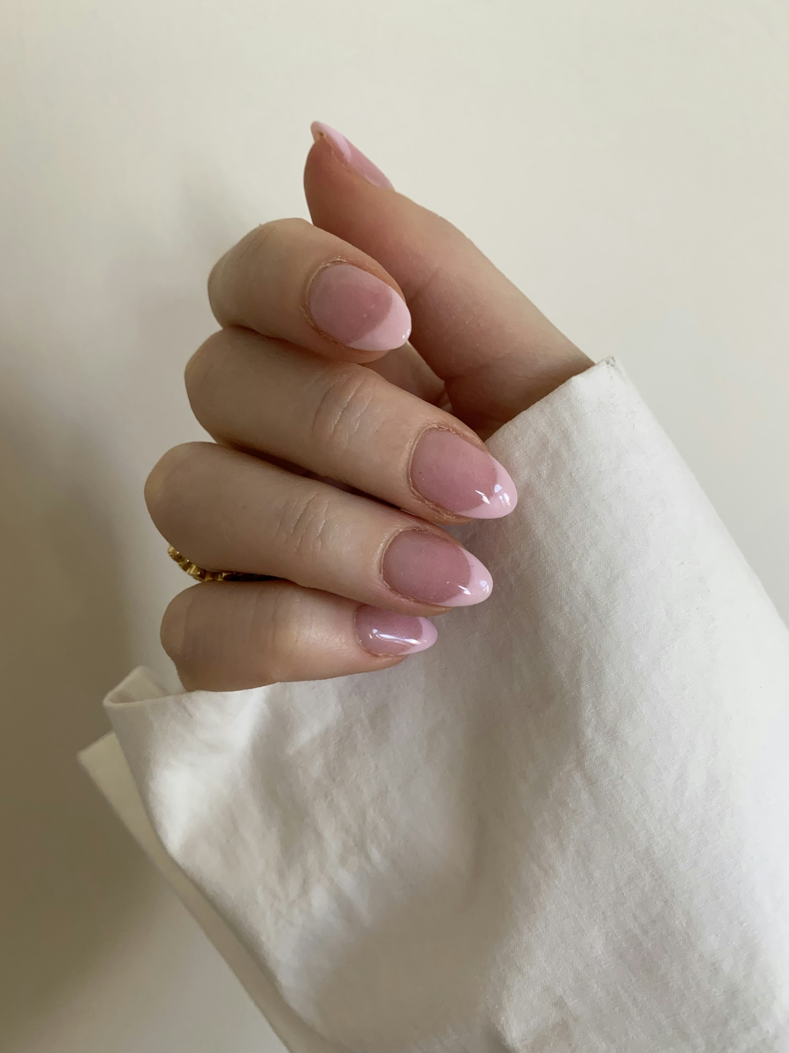 Unhas arredondadas com esmaltação rosa delicada e acabamento brilhante